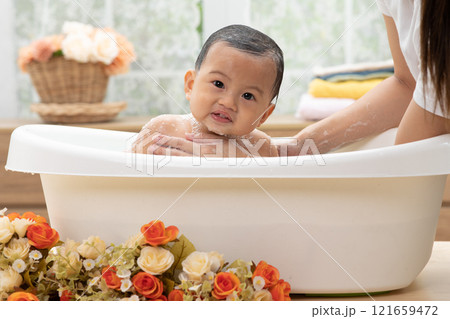 Adorable of asian newborn baby bathing in bathtub.mother bathing her son in warm water.Happy adorable newborn infant smile in tub relax and comfortable.Newborn baby care concept Adorable of asian newborn baby bathing in bathtub.mother bathing her son in warm water.Happy adorable newborn infant smile in tub relax and comfortable.Newborn baby care concept 121659472