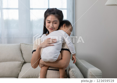 Happy Asian mother holding a cute newborn baby sleep on arm comfort and safety. Happy infant baby sleep with mother standing near windows warm and relax. Good moment. Mom and Baby care Concept 121659519