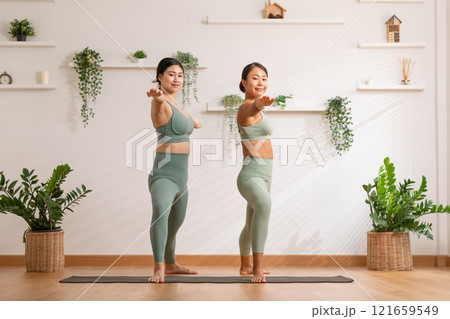 Couple and paired Asian young woman on yoga mat doing breathing exercise yoga together.Yoga meditation of two healthy female balancing body and relax at cozy home. Self care concept Couple and paired Asian young woman on yoga mat doing breathing exercise yoga together.Yoga meditation of two healthy female balancing body and relax at cozy home. Self care concept 121659549