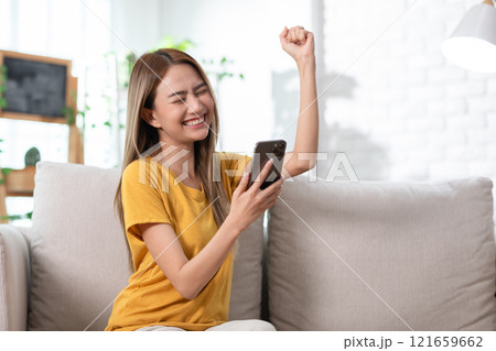 Exuberant young woman in a yellow t-shirt jubilantly celebrating good news on her mobile phone Exuberant young woman in a yellow t-shirt jubilantly celebrating good news on her mobile phone 121659662