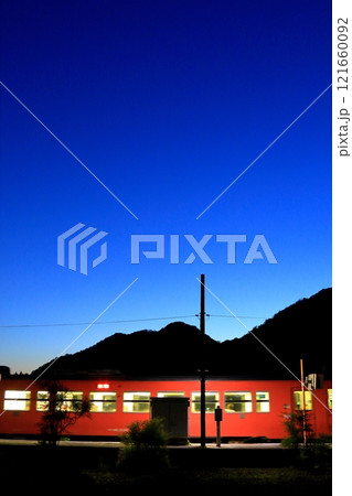 黄昏時の駅から動き始める列車 121660092