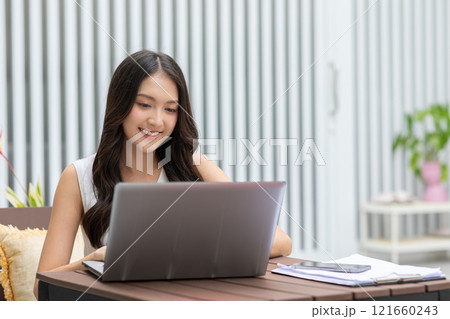 beautiful asian young woman wear casual sit on couch using computer laptop entertain with social media relax smile and laughing.Freelance woman working online sale marketing. Shopping online at home 121660243
