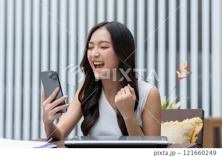 Millennial asian young woman looking mobile phone laughing with good news or discount voucher for shopping online at home.Happy and cheerful woman looking on cellphone app read message feel excited Millennial asian young woman looking mobile phone laughing with good news or discount voucher for shopping online at home.Happy and cheerful woman looking on cellphone app read message feel excited 121660249