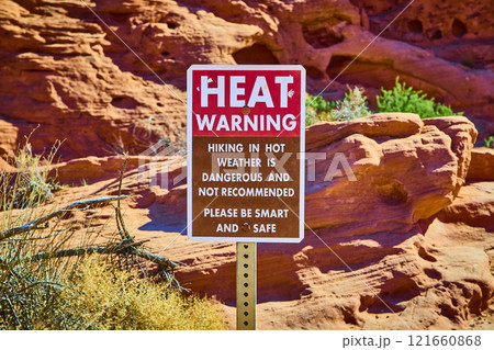 Desert Heat Warning Sign with Red Rock Formations Eye-Level View 121660868