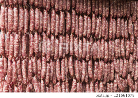 Close-up of ungrilled Taiwanese sausage bunches hanging on wooden sticks. This is one of the street snacks popular among tourists in Taiwan. Close-up of ungrilled Taiwanese sausage bunches hanging on wooden sticks. This is one of the street snacks popular among tourists in Taiwan. 121661079