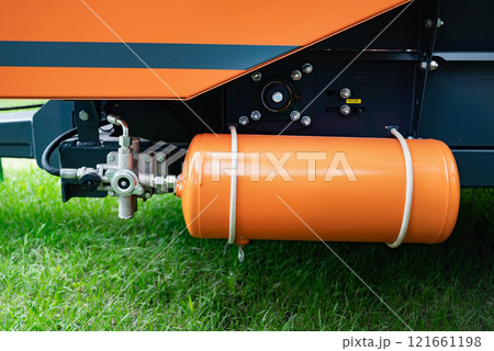 Close-up of orange gas cylinder attached to machinery. Close-up of orange gas cylinder attached to machinery. 121661198