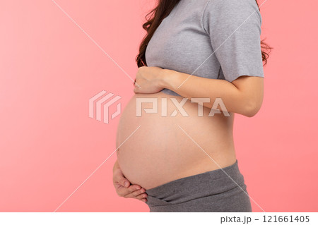 Side view Close up Pregnant Woman standing stroking big belly with love isolated on pink background. Pregnancy of young woman enjoy with future life. Motherhood and Pregnant Concept Side view Close up Pregnant Woman standing stroking big belly with love isolated on pink background. Pregnancy of young woman enjoy with future life. Motherhood and Pregnant Concept 121661405