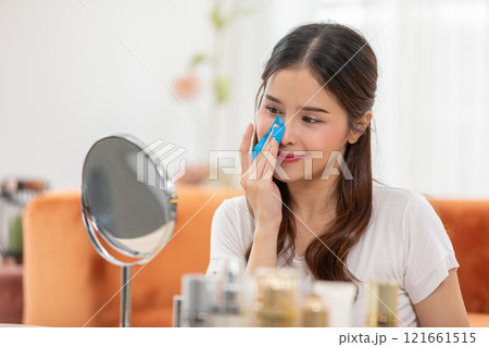 Woman Using Oil-Absorbing Film for Skincare in Bright Room 121661515
