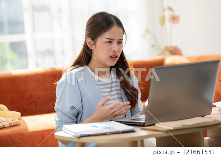 Asian Frustrated Woman Working on Laptop with Documents at Home 121661531