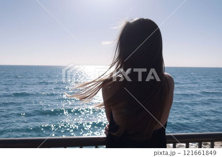 輝く海と晴れた空を見つめる女性 121661849