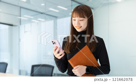 スマホとバインダーを持つ笑顔の女性・ビジネスウーマン 121662078