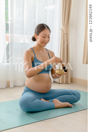 Pregnant woman practices meditation with a singing bowl, promoting relaxation and mindfulness during pregnancy. Calm, serene indoor setting. Pregnant woman practices meditation with a singing bowl, promoting relaxation and mindfulness during pregnancy. Calm, serene indoor setting. 121662149