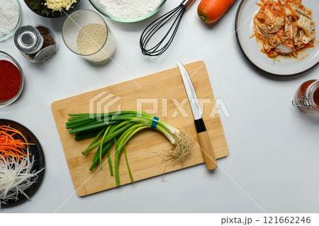 Fresh green onions on a wooden cutting board surrounded by ingredients for preparing traditional Kimchi Fresh green onions on a wooden cutting board surrounded by ingredients for preparing traditional Kimchi 121662246