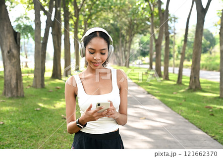 Smiling active woman using mobile phone to track workout progress in the park Smiling active woman using mobile phone to track workout progress in the park 121662370