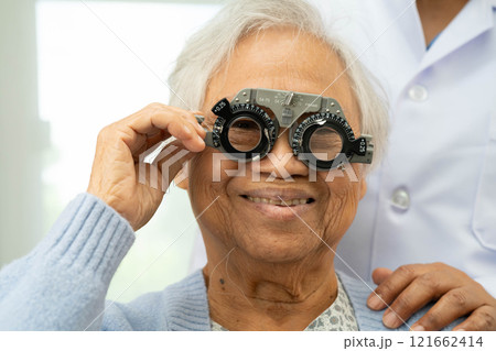 Optometrist checking Asian elderly woman ophthalmic vision eye test and using optical trial frame. 121662414