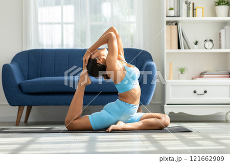 Asian woman finding peace and balance through yoga practice in the comfort of her home. Promoting wellness, mindfulness, and self care. Perfect for yoga and home wellness concepts Asian woman finding peace and balance through yoga practice in the comfort of her home. Promoting wellness, mindfulness, and self care. Perfect for yoga and home wellness concepts 121662909