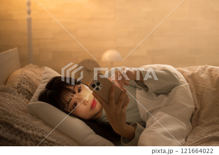 夜中にスマホを見て睡眠が足りず寝不足になってしまう女性のクローズアップでタップする　黄色 121664022