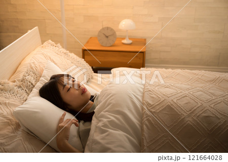 間接照明で眠りにつく女性 ベッドの睡眠や安眠のイメージの横顔 間接照明で眠りにつく女性 ベッドの睡眠や安眠のイメージの横顔 121664028