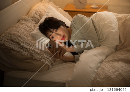 夜中にスマホを見て睡眠が足りず寝不足になってしまう女性のクローズアップでタップする　黄色 121664033