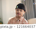 Asian cheerful young boy with Down syndrome enjoys playing with bubbles indoors. His bright smile and playful gestures capture the innocence and joy of childhood 121664037