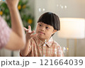Asian cheerful young boy with Down syndrome enjoys playing with bubbles indoors. His bright smile and playful gestures capture the innocence and joy of childhood 121664039