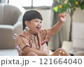 Asian cheerful young boy with Down syndrome enjoys playing with bubbles indoors. His bright smile and playful gestures capture the innocence and joy of childhood 121664040