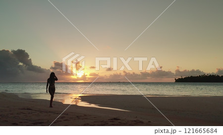 Woman walking sunset beach tropical Maldives island. Slim female silhouette relax, enjoy outdoor lifestyle travel on summer holiday vacation. Beautiful coastline nature landscape. Panorama drone shot 121665684