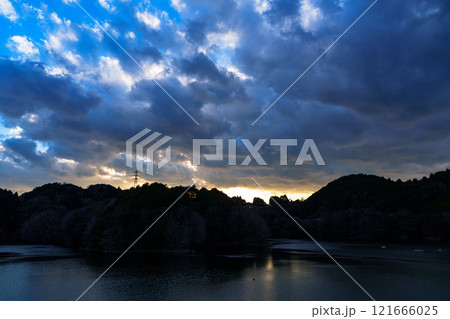 新春の奈良布目ダム寒風吹きすさぶ夕景 山際で輝く黄金色の空と上空に向かって千切れバラバラになる雲 新春の奈良布目ダム寒風吹きすさぶ夕景 山際で輝く黄金色の空と上空に向かって千切れバラバラになる雲 121666025