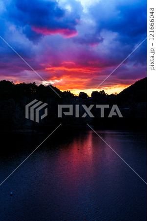 新春の奈良布目ダム寒風吹きすさぶ夕景　紺色の空と湖面に囲まれた燃えるような夕焼けの空と湖面③ 121666048
