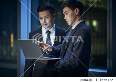 two asian businessmen discussing business in office using laptop computer 121666472