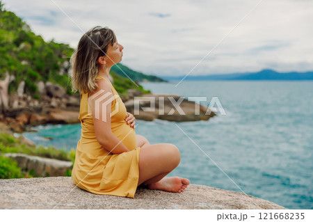 Pregnant female in dress relaxing at sea coastline Pregnant female in dress relaxing at sea coastline 121668235