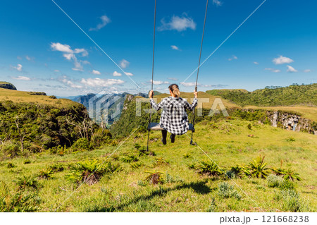 Woman ride a swing in the middle of a picturesque mountain landscape in Brasil 121668238