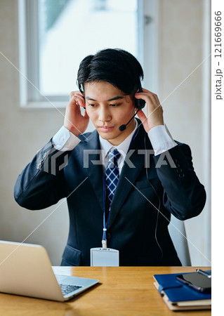 オフィスで電話対応をする20代の若い男性 オフィスで電話対応をする20代の若い男性 121669666