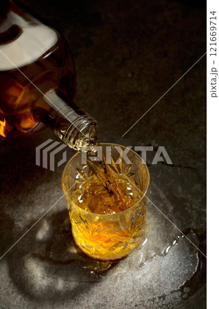 Whisky pour from a bottle into a crystal glass. Whisky pour from a bottle into a crystal glass. 121669714