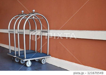 Retro luggage carts near the hotel entrance, Metal luggage trolley in front of orange wall with copy space. 121670549