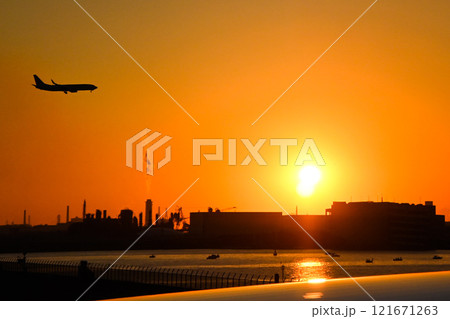 東京湾のシルエットと夕日、羽田空港に着陸する旅客機 121671263