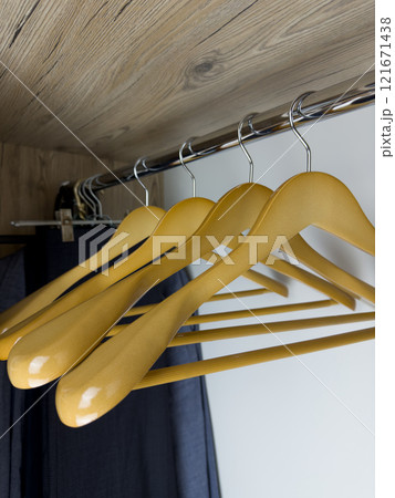 Close up photo of wooden clothes hangers inside clothes closet, empty hangers for easy storage of clean clothes at home inside wardrobe, durable wooden hangers on beam in wardrobe Close up photo of wooden clothes hangers inside clothes closet, empty hangers for easy storage of clean clothes at home inside wardrobe, durable wooden hangers on beam in wardrobe 121671438