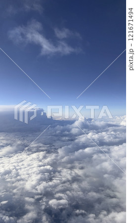View above clouds on blue sky background. View from airplane window. View above clouds on blue sky background. View from airplane window. 121671494