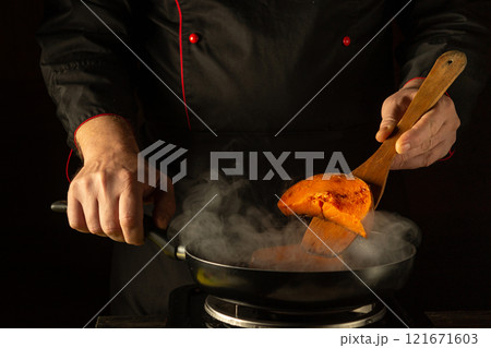 A chef expertly flips a vibrant orange ingredient in a sizzling pan. Steam rises, filling the air with enticing aromas, showcasing culinary expertise in a stylish kitchen environment A chef expertly flips a vibrant orange ingredient in a sizzling pan. Steam rises, filling the air with enticing aromas, showcasing culinary expertise in a stylish kitchen environment 121671603