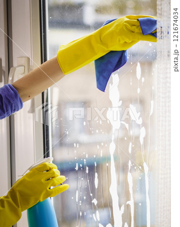 Gloved hand cleaning window rag and spray Gloved hand cleaning window rag and spray 121674034