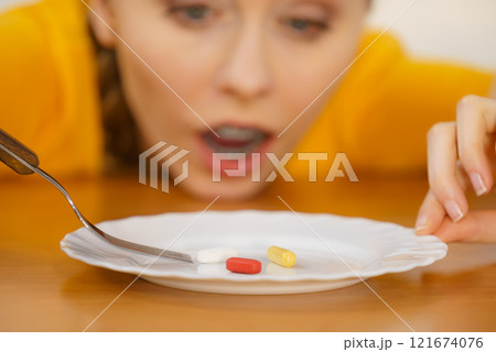 Shocked woman having pills on plate 121674076