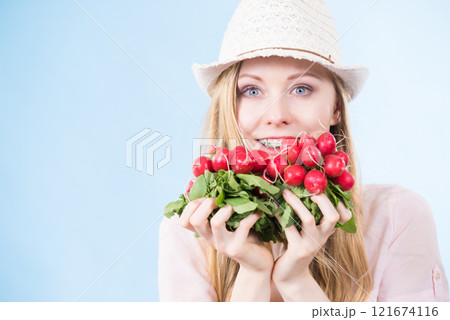 woman holding radish close to face woman holding radish close to face 121674116