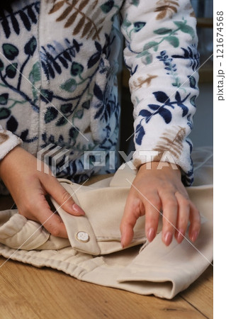 A woman is examining classic beige trousers. She is demonstrating the design elements. Close-up. 121674568