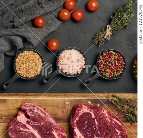 Raw beef steak chuck eye roll on wooden board. Spices for cooking Himalayan salt, peppercorns and thyme sprigs, top view Raw beef steak chuck eye roll on wooden board. Spices for cooking Himalayan salt, peppercorns and thyme sprigs, top view 121676045