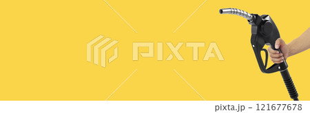 Hands holding Fuel nozzle on yellow background Hands holding Fuel nozzle on yellow background 121677678