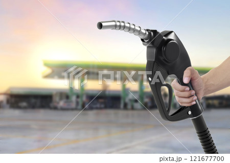 Holding a fuel nozzle against with gas station blurred background 121677700