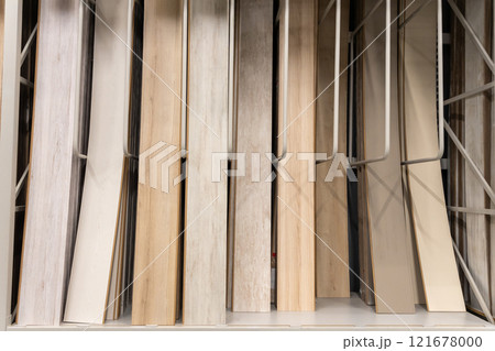 A close-up of various wooden laminate textures and colors displayed on racks in a home improvement store 121678000