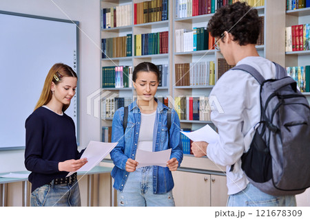 Group of college students teenage girls and guy talking inside library classroom Group of college students teenage girls and guy talking inside library classroom 121678309