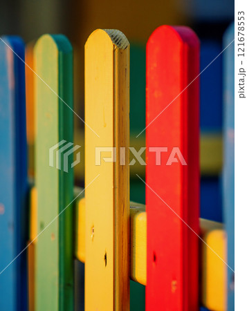The colorful painted wooden boards on the fence around a playground are illuminated by the rays of the setting sun. Pula, Croatia - January 3, 2025 The colorful painted wooden boards on the fence around a playground are illuminated by the rays of the setting sun. Pula, Croatia - January 3, 2025 121678553