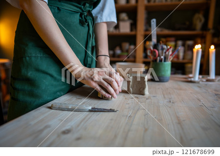 Craftswoman hands kneading clay for crafting natural pottery on table in workshop. Small business Craftswoman hands kneading clay for crafting natural pottery on table in workshop. Small business 121678699